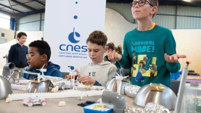 Des enfants construisent une maquette de base spatiale autour d'une table