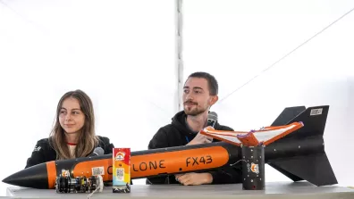 Deux étudiants assis à une table où se trouve une mini-fusée