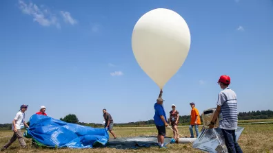 Plusieurs participants se préparent à lâcher un ballon-sonde sur un terrain vague