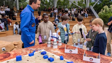 Journée Proximars, un intervenant est entouré d'enfants autour d'une table contenant des projets et des maquettes