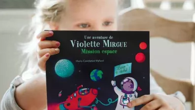 Une petite fille tenant un livre sur le thème de l'espace
