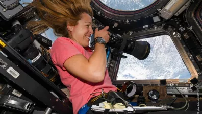 Sophie Adenot à bord de l'ISS, dans la Cupola, tenant un appareil photo